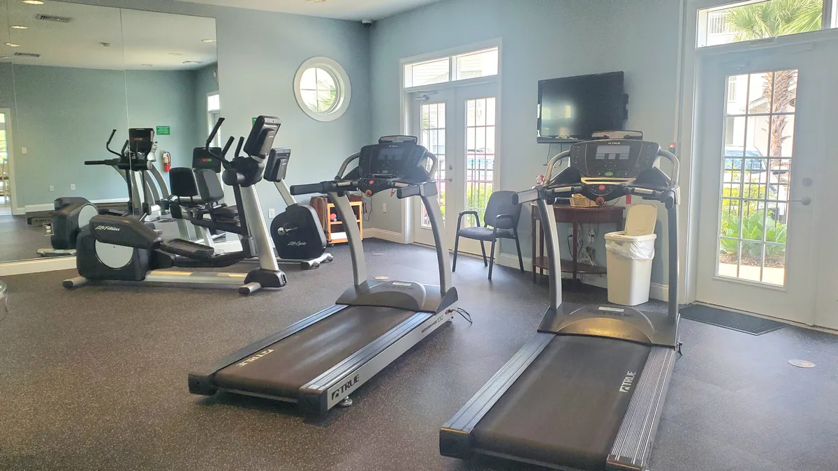 The resort’s modern fitness center is pictured here, featuring state-of-the-art treadmills and elliptical machines positioned in front of large windows. A mirrored wall expands the sense of space and energy, and the layout suggests a motivating, friendly environment for both solo workouts and group classes.